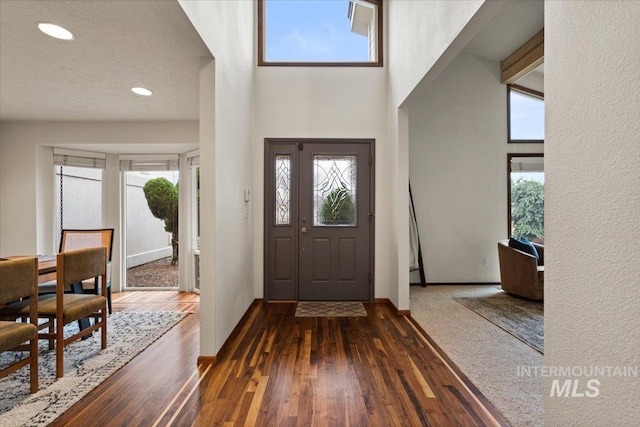 foyer featuring recessed lighting, baseboards, a high ceiling, and dark wood-style floors