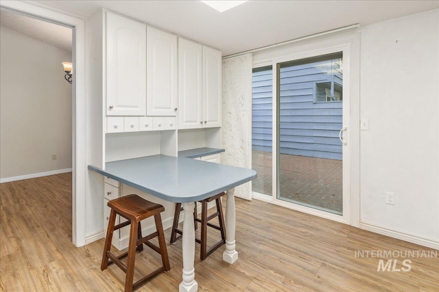 kitchen with light hardwood / wood-style flooring, a kitchen breakfast bar, and white cabinets