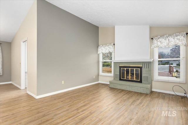 unfurnished living room featuring lofted ceiling, a fireplace, and light hardwood / wood-style floors