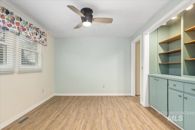 unfurnished room with ceiling fan, light hardwood / wood-style floors, and a textured ceiling