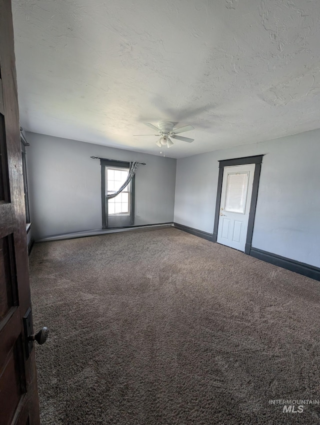 empty room featuring carpet flooring, a ceiling fan, baseboards, and a textured ceiling