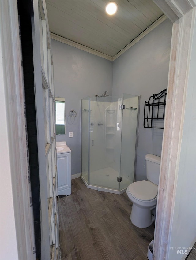 bathroom featuring vanity, toilet, a shower stall, wood finished floors, and ornamental molding