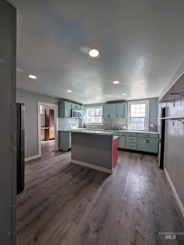 kitchen featuring baseboards, dark wood-style flooring, stainless steel microwave, and a wealth of natural light