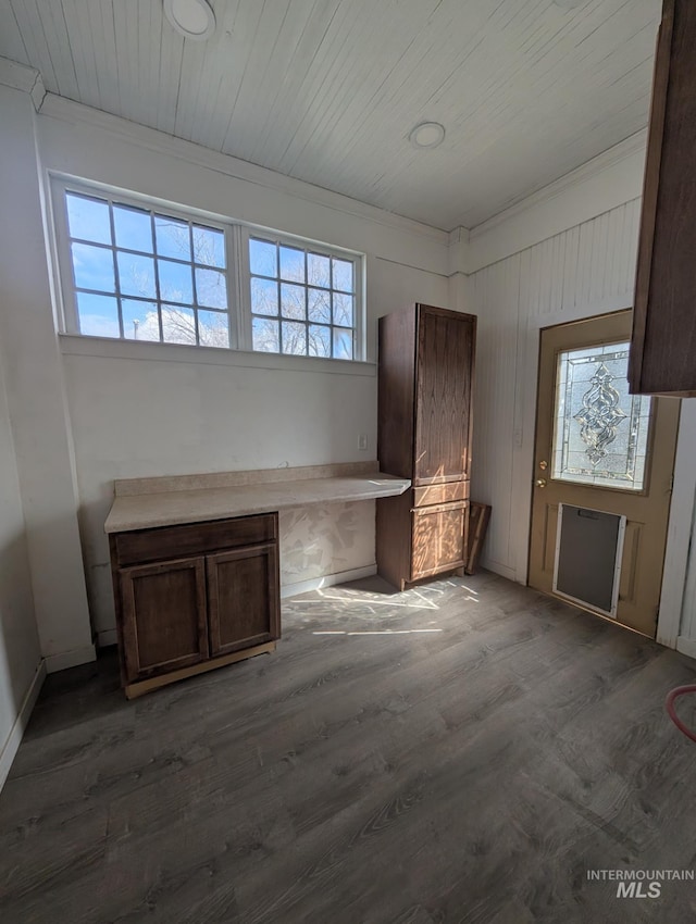 unfurnished living room with crown molding, wood ceiling, plenty of natural light, and dark wood-style flooring
