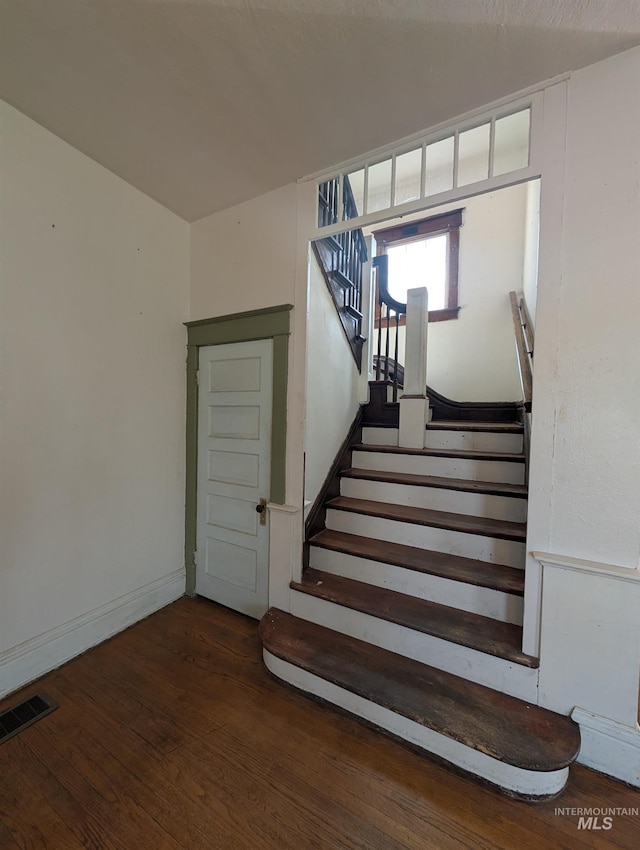 stairs with baseboards, visible vents, and wood finished floors
