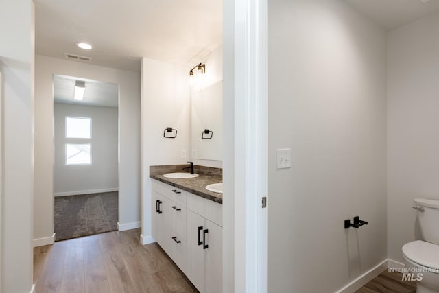 bathroom with toilet, baseboards, visible vents, and wood finished floors