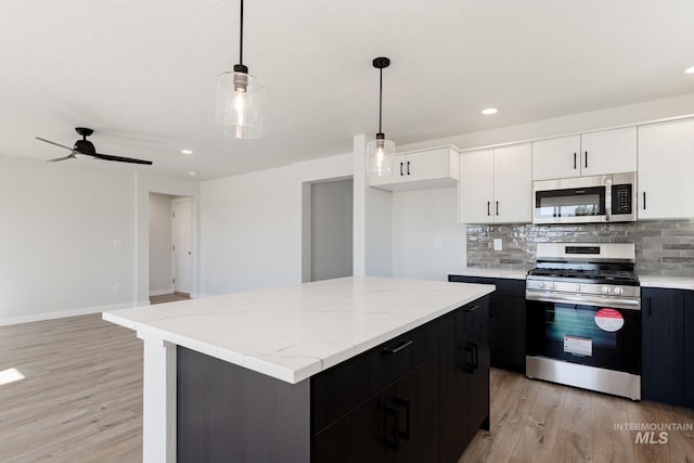 kitchen with white cabinets, light wood-style floors, stainless steel appliances, and decorative backsplash