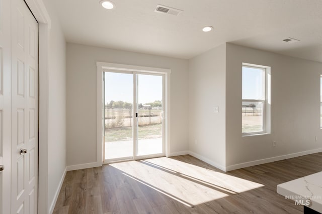 spare room with baseboards, visible vents, and wood finished floors