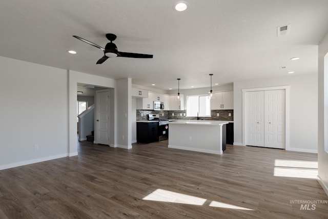 kitchen featuring appliances with stainless steel finishes, open floor plan, white cabinets, and backsplash