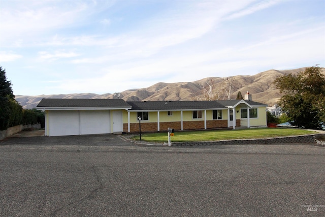 ranch-style house with a mountain view, a garage, and a front lawn