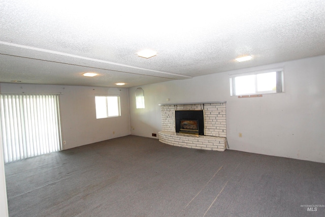 unfurnished living room with carpet flooring, a textured ceiling, and a fireplace