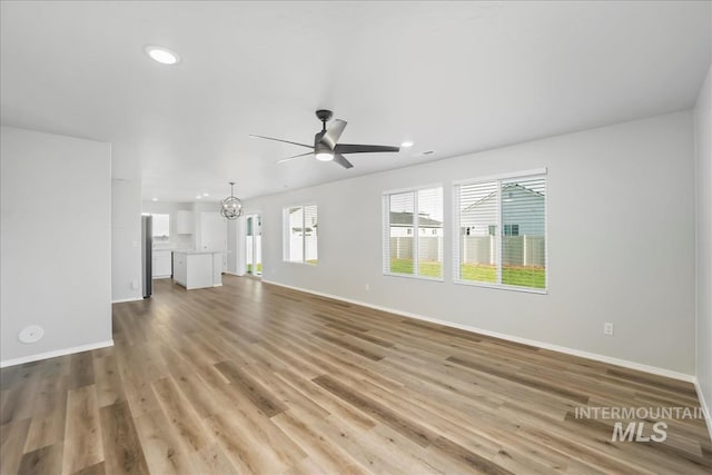 709 W Smoky Quartz St, Kuna, ID 83634 - unfurnished living room featuring baseboards, a chandelier, light wood-style floors, and recessed lighting