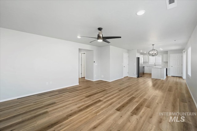 709 W Smoky Quartz St, Kuna, ID 83634 - unfurnished living room with a chandelier, baseboards, ceiling fan, light wood-type flooring, and recessed lighting