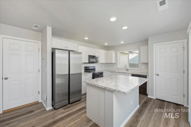 709 W Smoky Quartz St, Kuna, ID 83634 - kitchen featuring black appliances, a sink, a kitchen island, white cabinetry, and wood finished floors
