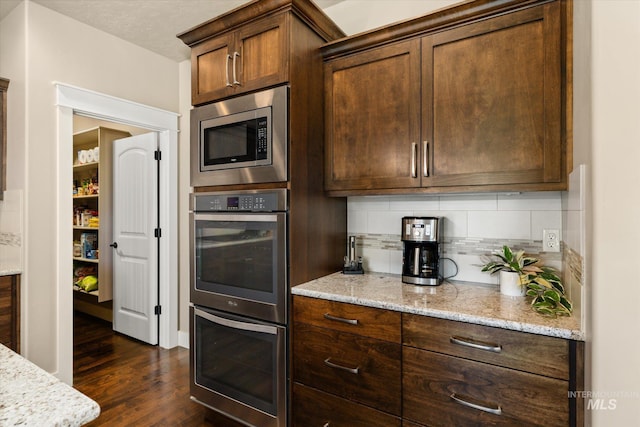 11714 W Pinewood River Ln, Star, ID 83669 - kitchen featuring stainless steel appliances, backsplash, dark wood-type flooring, light stone countertops, and dark brown cabinets