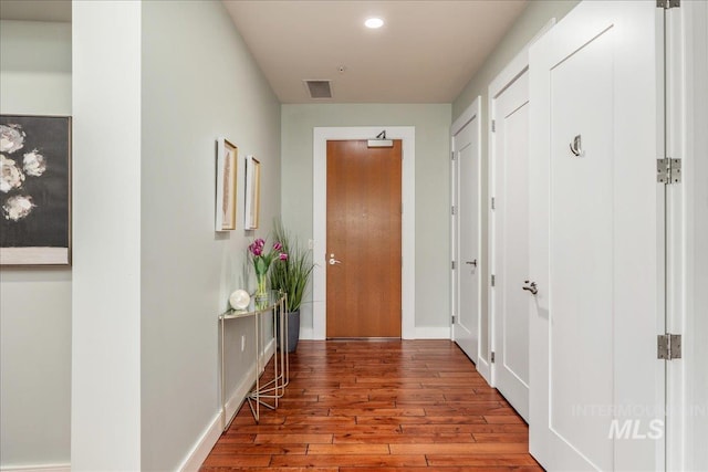 hallway featuring visible vents, recessed lighting, baseboards, and hardwood / wood-style flooring