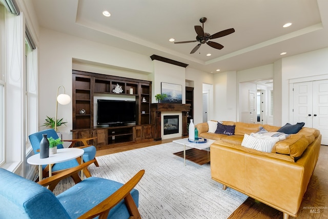 6859 N Topaz Jewel Pl, Meridian, ID 83646 - living room with a tray ceiling, ceiling fan, wood finished floors, recessed lighting, and a glass covered fireplace