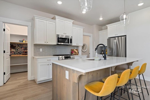1867 W Wind Drift St, Meridian, ID 83646 - kitchen with appliances with stainless steel finishes, a sink, decorative backsplash, light wood-style flooring, and light countertops