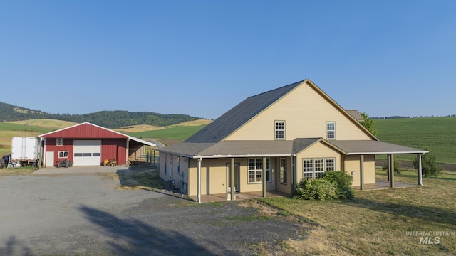 farmhouse inspired home with a garage, covered porch, dirt driveway, and an outdoor structure