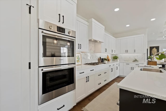 kitchen with dark wood-type flooring, sink, appliances with stainless steel finishes, decorative backsplash, and white cabinets