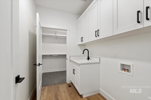 clothes washing area featuring cabinets, washer hookup, light hardwood / wood-style floors, and sink