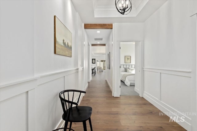 corridor featuring hardwood / wood-style flooring, a chandelier, and a tray ceiling