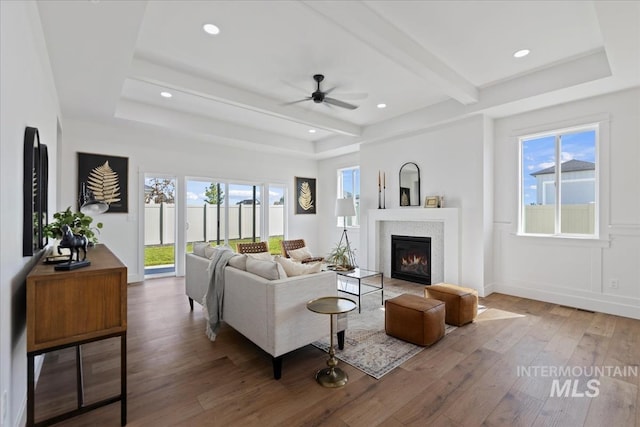 living room with beamed ceiling, wood-type flooring, a healthy amount of sunlight, and ceiling fan