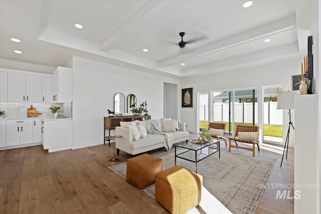 living room with ceiling fan, light hardwood / wood-style flooring, and beamed ceiling