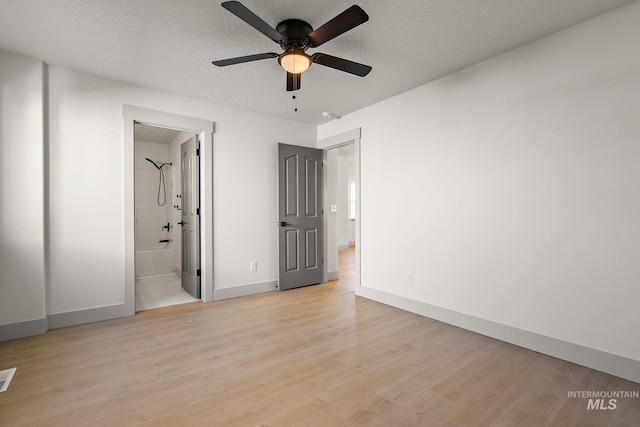 unfurnished bedroom with light wood-type flooring, baseboards, a textured ceiling, and ensuite bathroom