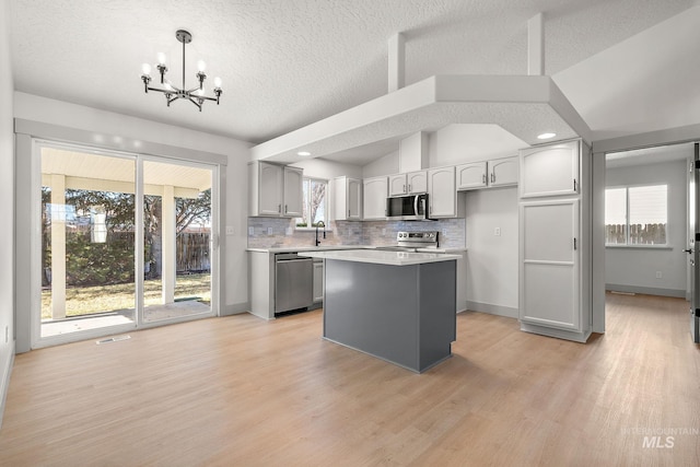 kitchen featuring a chandelier, visible vents, vaulted ceiling, appliances with stainless steel finishes, and decorative backsplash