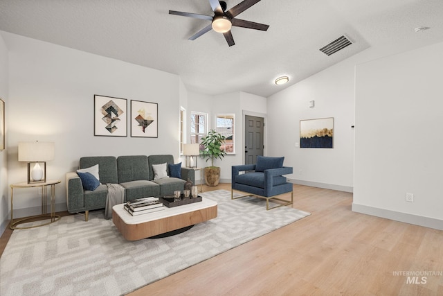 living area with baseboards, visible vents, a ceiling fan, wood finished floors, and vaulted ceiling