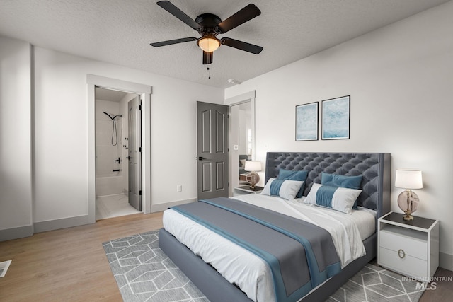 bedroom featuring ensuite bath, a textured ceiling, baseboards, and wood finished floors