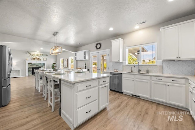 120 Pilgrim Way, Middleton, ID 83644 - kitchen with a sink, appliances with stainless steel finishes, open floor plan, a textured ceiling, and white cabinetry