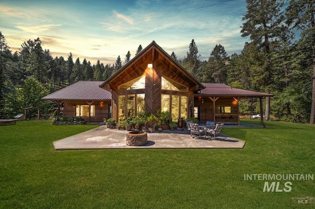 back house at dusk with a yard, a patio, and an outdoor fire pit