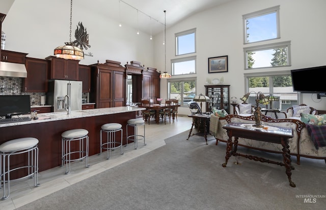 110 S 3rd Ave, Pierce, ID 83546 - kitchen featuring under cabinet range hood, stainless steel fridge, high vaulted ceiling, a kitchen bar, and plenty of natural light