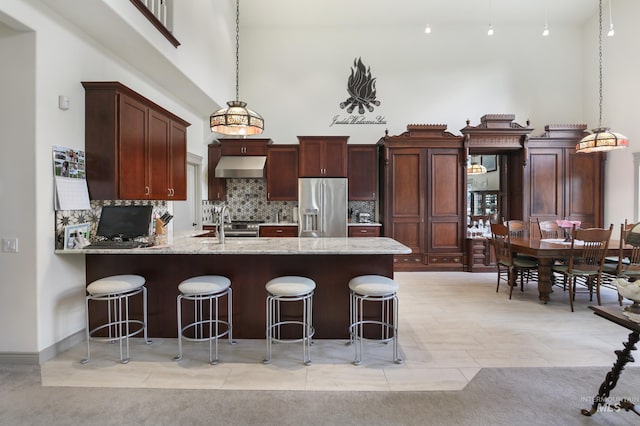 110 S 3rd Ave, Pierce, ID 83546 - kitchen featuring stainless steel fridge with ice dispenser, under cabinet range hood, decorative backsplash, pendant lighting, and a towering ceiling