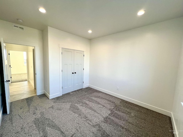 unfurnished bedroom featuring baseboards, visible vents, dark carpet, and recessed lighting