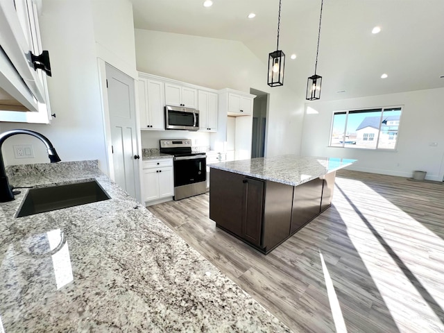 kitchen with white cabinets, light wood-style floors, stainless steel appliances, and a sink