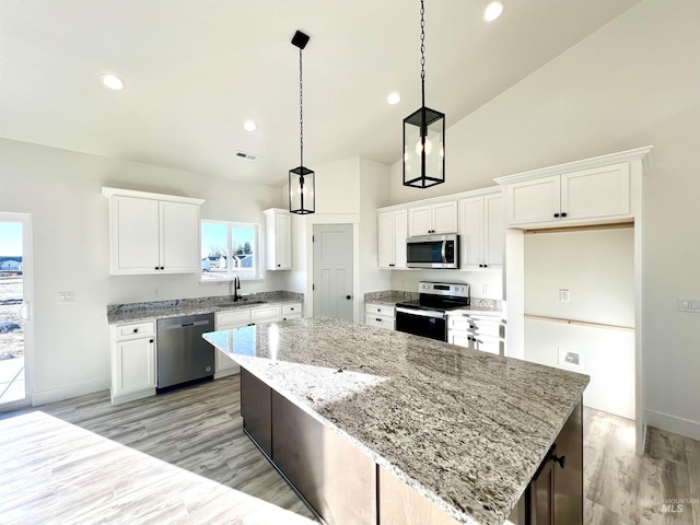 kitchen featuring visible vents, a center island, stainless steel appliances, light wood-style floors, and white cabinetry