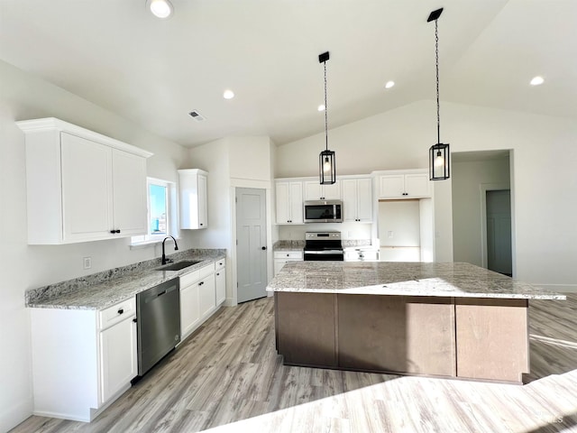 kitchen with appliances with stainless steel finishes, white cabinets, a sink, and a kitchen island