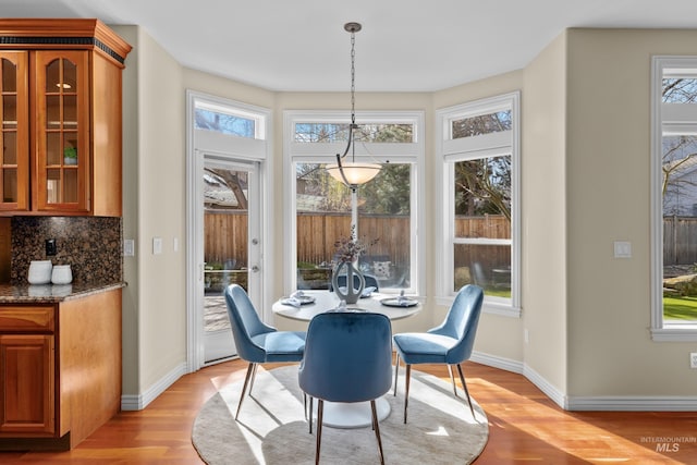 dining area with a wealth of natural light, baseboards, and light wood-style floors