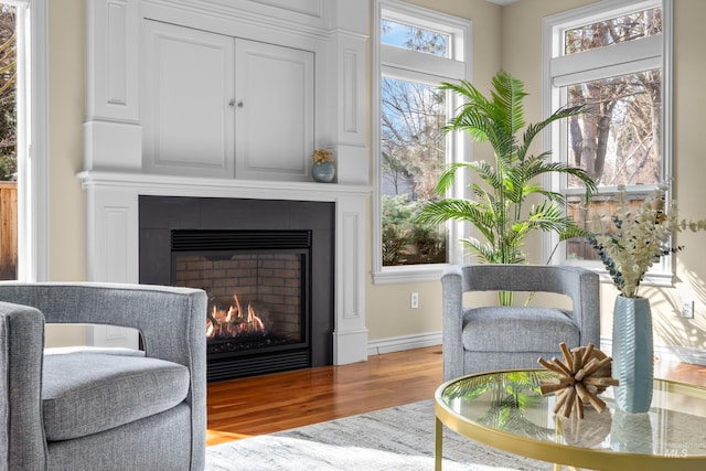 sitting room with wood finished floors and a warm lit fireplace