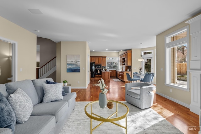 living area featuring recessed lighting, light wood-type flooring, baseboards, and stairs