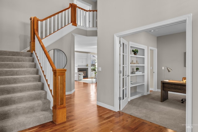 stairway with baseboards, a high ceiling, wood finished floors, and a fireplace