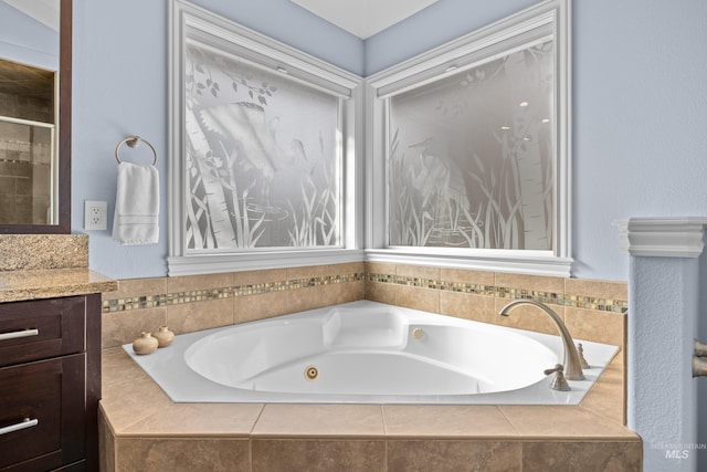 full bath featuring a stall shower, vanity, and a whirlpool tub