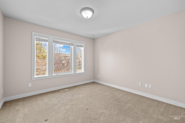 carpeted empty room featuring baseboards and visible vents