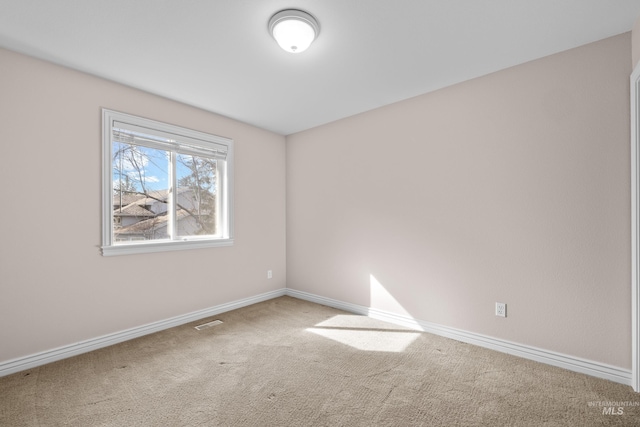 carpeted empty room featuring baseboards and visible vents