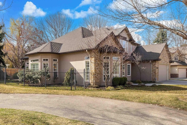 view of front of home featuring brick siding, a fenced front yard, a garage, and a front lawn