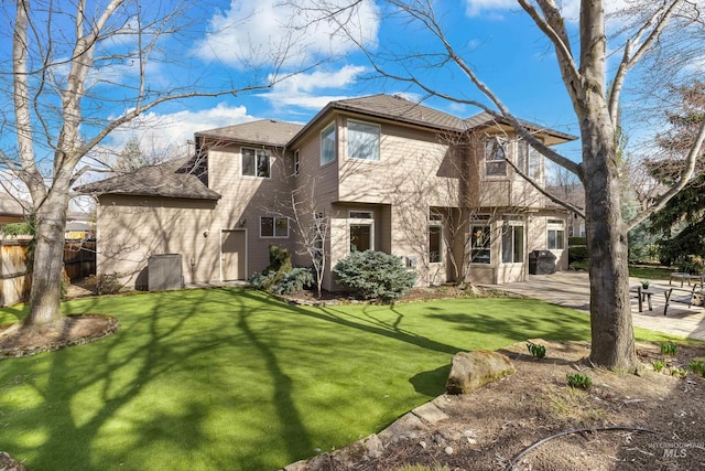 back of house featuring a patio area, a lawn, and fence