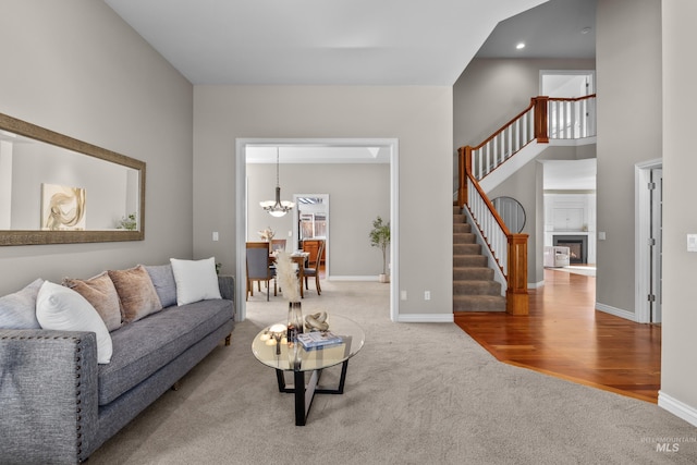 living area with a glass covered fireplace, stairs, carpet flooring, and baseboards